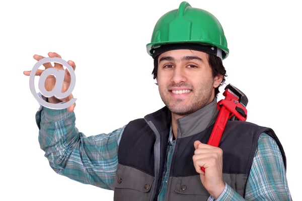A handyman holding a at sign. — Stock Photo, Image