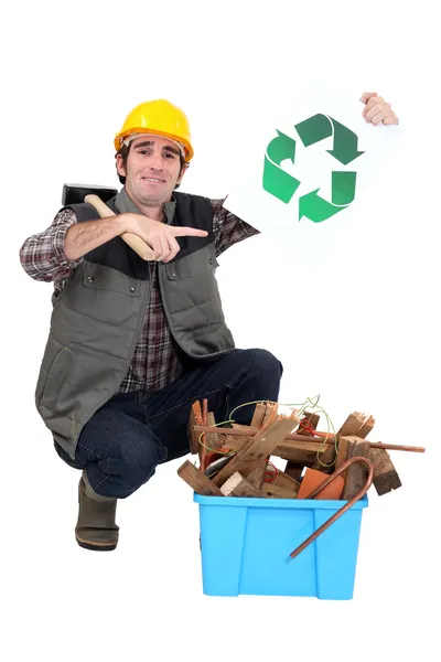 Handwerker kniet neben einer Tonne und hält das Recycling-Symbol hoch — Stockfoto