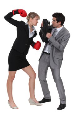 Businesswoman threatening male colleague with boxing gloves clipart
