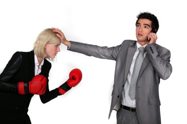 Businesswoman with boxing gloves and male colleague on the phone clipart