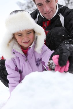 Father and daughter building snow-pile clipart