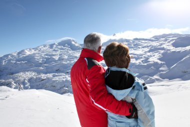 Middle-aged couple stood on secluded snowy mountain clipart