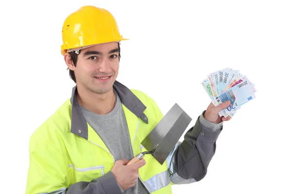 Tradesman holding a trowel and cash — Stock Photo, Image