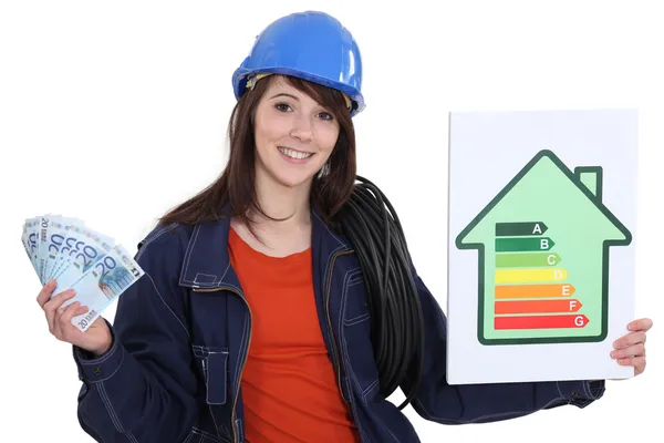 Electrician holding cash and an energy rating sign — Stock Photo, Image