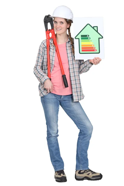 Tradeswoman holding oversized pliers and an energy efficiency rating sign — Stock Photo, Image