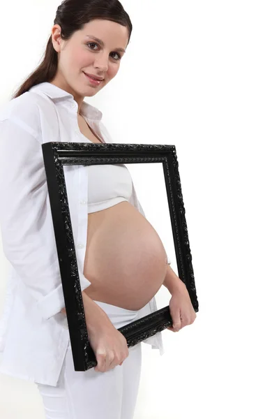 Woman holding her pregnant tummy in a frame — Stock Photo, Image