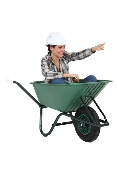 Female tradesperson sitting in a wheelbarrow — Stock Photo, Image