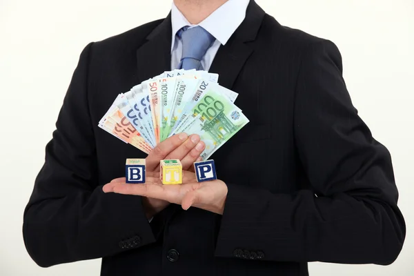 Businessman holding bills and toy blocks — Stock Photo, Image
