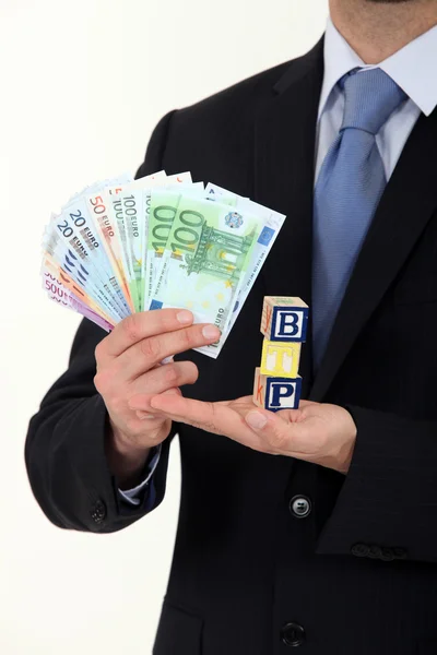 Businessman holding cash and the letters BTP — Stock Photo, Image