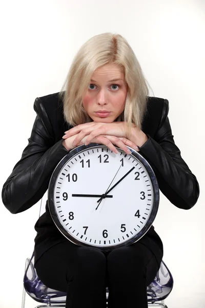 Женщина, опирающаяся на настенные часы — стоковое фото