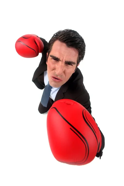 Businessman holding boxing gloves looking ferocious — Stock Photo, Image