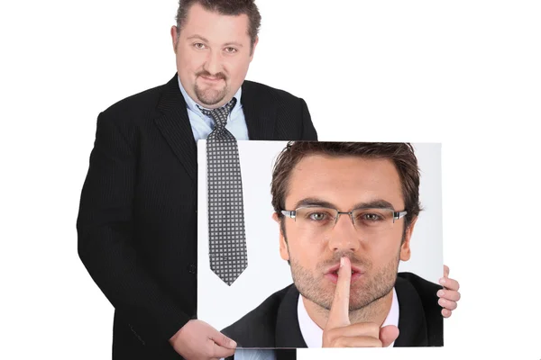 Moon-faced man wearing coat and tie showing picture of young man with finger in mouth — Stock Photo, Image
