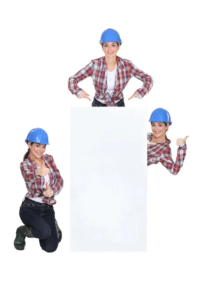 Construtora feminina atrás do quadro de mensagens em branco — Fotografia de Stock