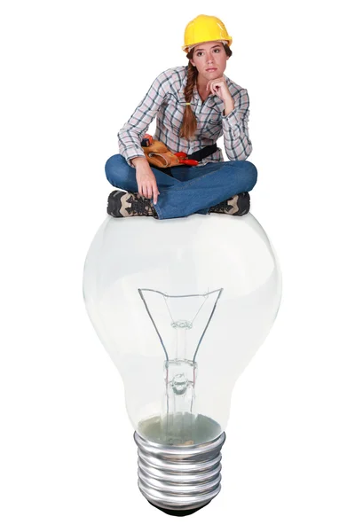 Arbeiterin sitzt auf einer Glühbirne — Stockfoto