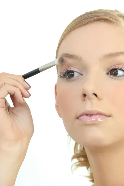 Mujer joven aplicando sombra de ojos — Foto de Stock