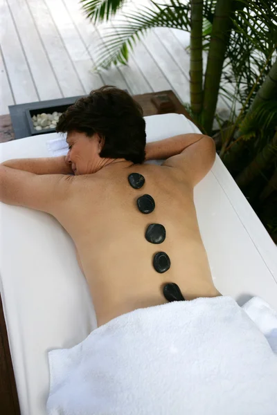 Mujer con piedras de masaje en la espalda — Foto de Stock