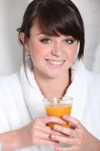 Morena en bata de baño sosteniendo vaso de jugo de naranja — Foto de Stock