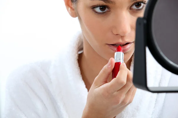 Kvinna som applicerar läppstift framför spegeln — Stockfoto