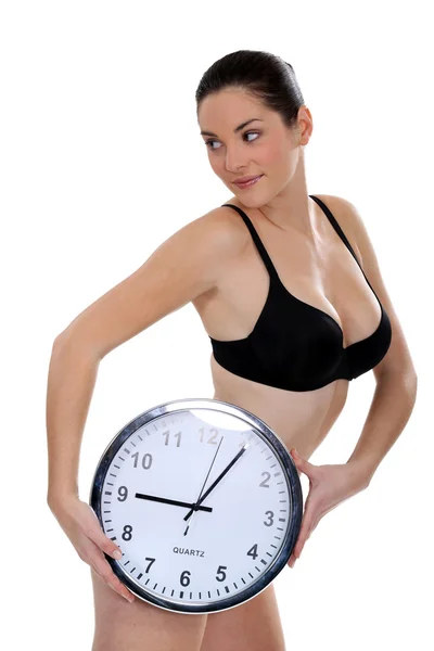 Kvinnan i hennes underkläder håller en stor klocka — Stockfoto