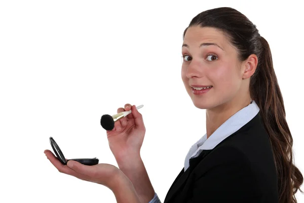 A businesswoman putting make-up on. — Stock Photo, Image