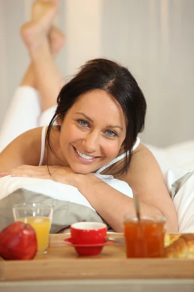 ベッドでの朝食とブルネットの女性 — ストック写真