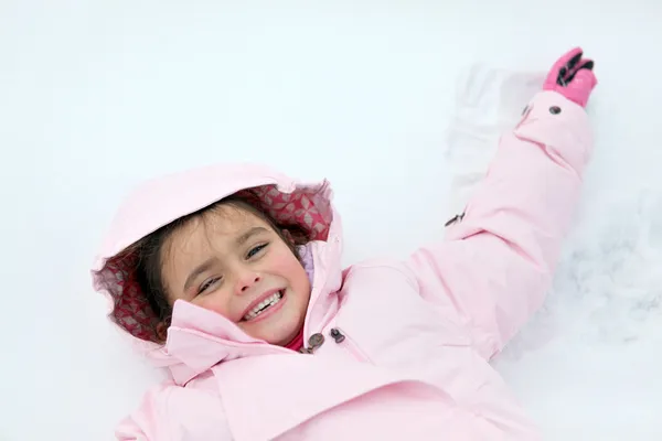 Маленька дівчинка лежить на снігу — стокове фото