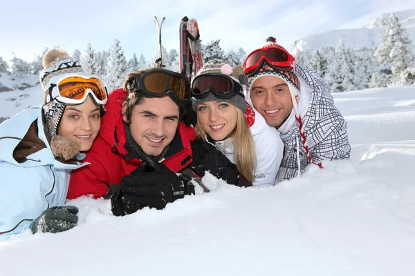 Vier jonge volwassenen leggen in de sneeuw — Stockfoto