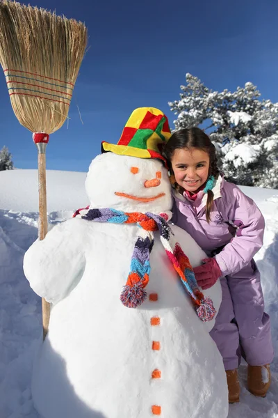 Девушка рядом со снеговиком — стоковое фото