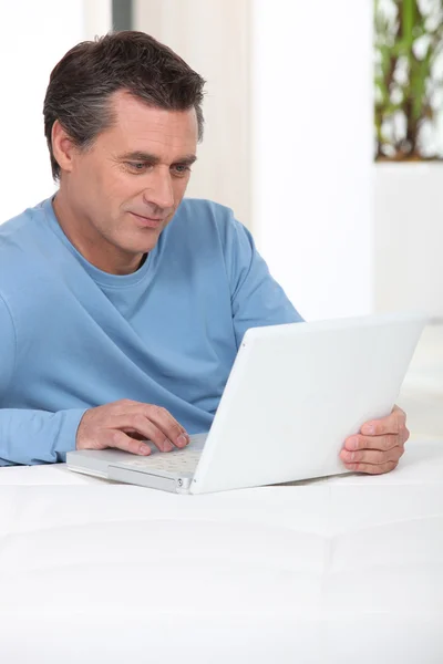 Άνθρωπος χρησιμοποιώντας φορητό υπολογιστή στο κρεβάτι του — Φωτογραφία Αρχείου