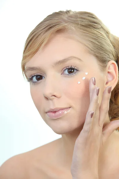 Young woman putting cream on her face Stock Picture
