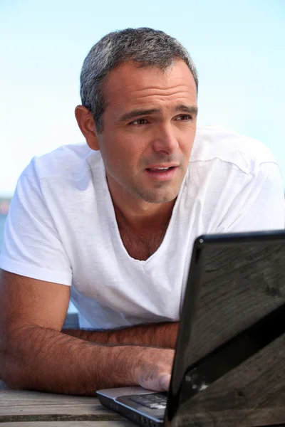 男子躺在码头与便携式计算机 图库图片
