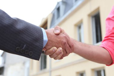 Couple shaking hands outside a house clipart