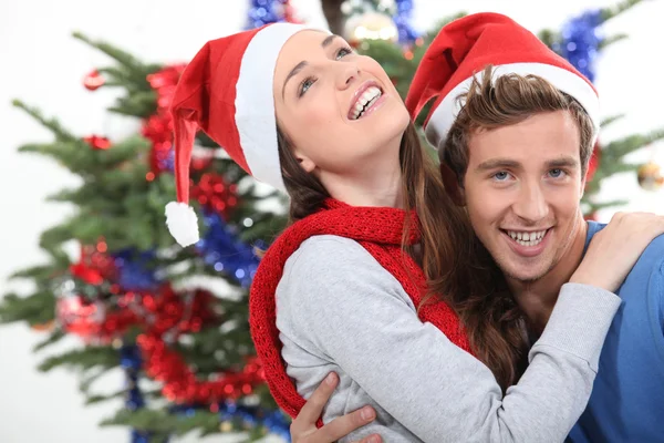 Una pareja abrazándose frente a un árbol de Navidad —  Fotos de Stock