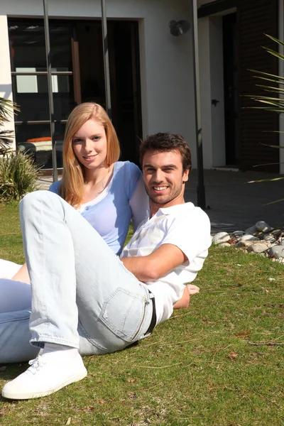 Unga paret sitter på gräsmattan — Stockfoto