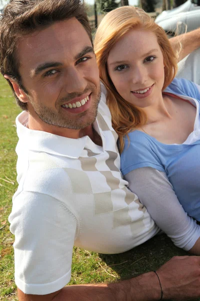 Молода пара сидить на газоні — стокове фото