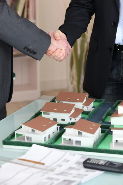 Aperto de mão sobre uma propriedade de habitação modelo — Fotografia de Stock