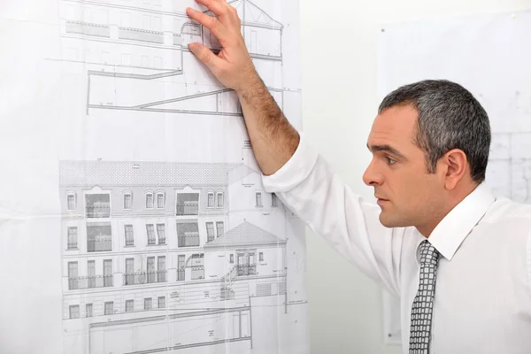 Arquitecto mirando planos pegados a la pared —  Fotos de Stock