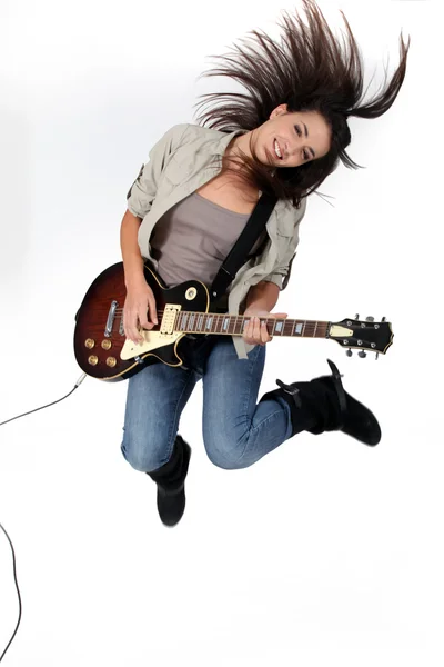 Mujer joven saltando y tocando la guitarra — Foto de Stock