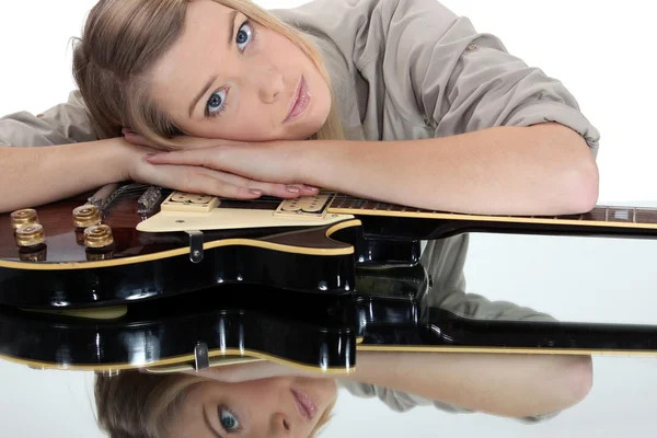 Jonge vrouw leunend op een gitaar — Stockfoto
