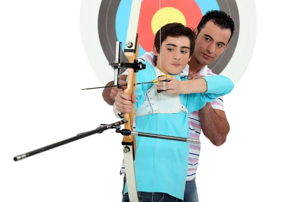 Homem ensinando tiro com arco a um menino — Fotografia de Stock