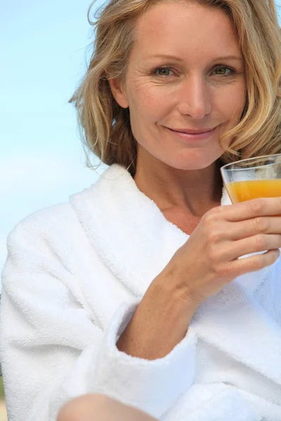 Woman in robe with glass of juice — Stock Photo, Image