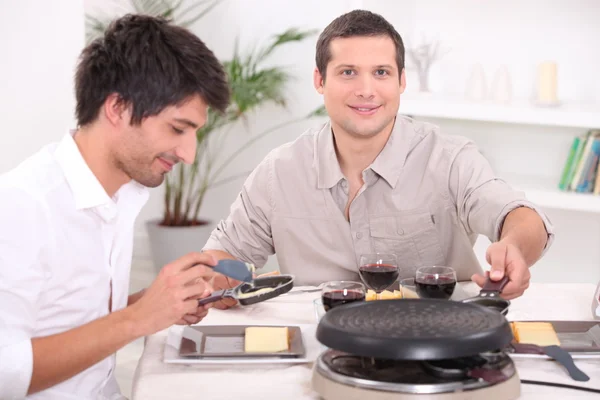 Zwei Männer genießen ein Raclette — Stockfoto