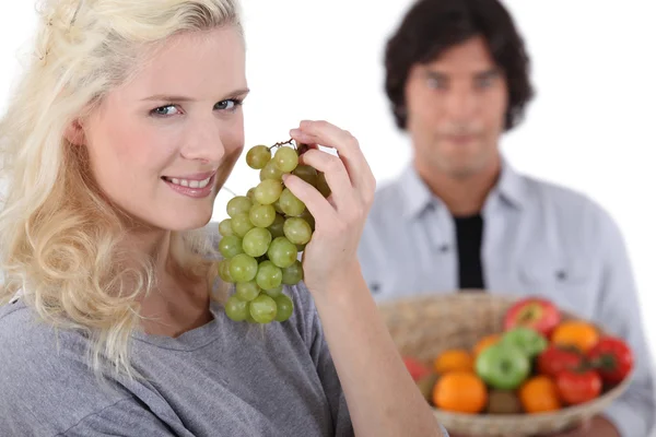 Hübsche lächelnde Blondine, die Weintrauben isst — Stockfoto