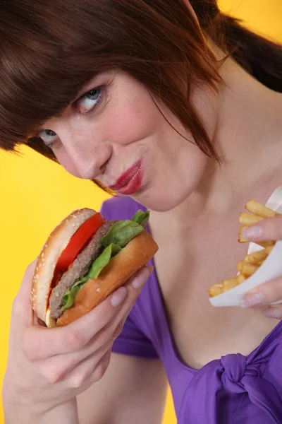 Mujer comiendo hamburguesa y patatas fritas —  Fotos de Stock