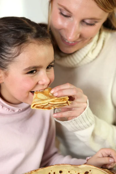 Girl and mom eating pancakes — Stock Photo, Image