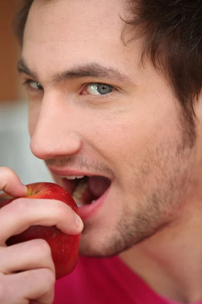 Ung man bita i rött äpple — Stockfoto