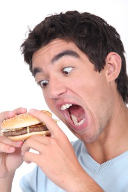 Young man taking an exaggerated bite out of a hamburger clipart