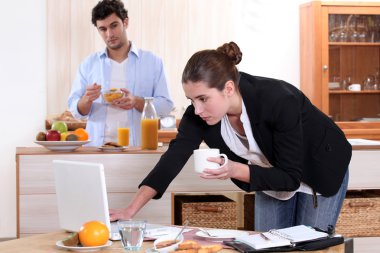 Woman working while eating breakfast clipart