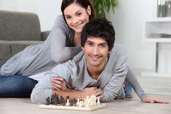 Couple laying on the floor playing chess — Stock Photo, Image