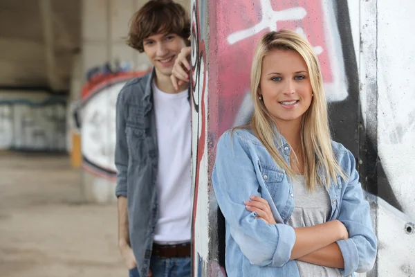 Attractive couples stood by graffiti covered wall — Stock Photo, Image